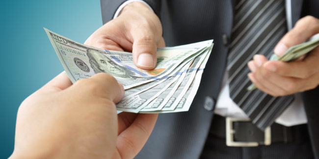 Two people exchanging cash Two people exchanging cash