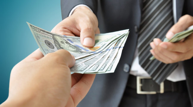 Two people exchanging cash Two people exchanging cash