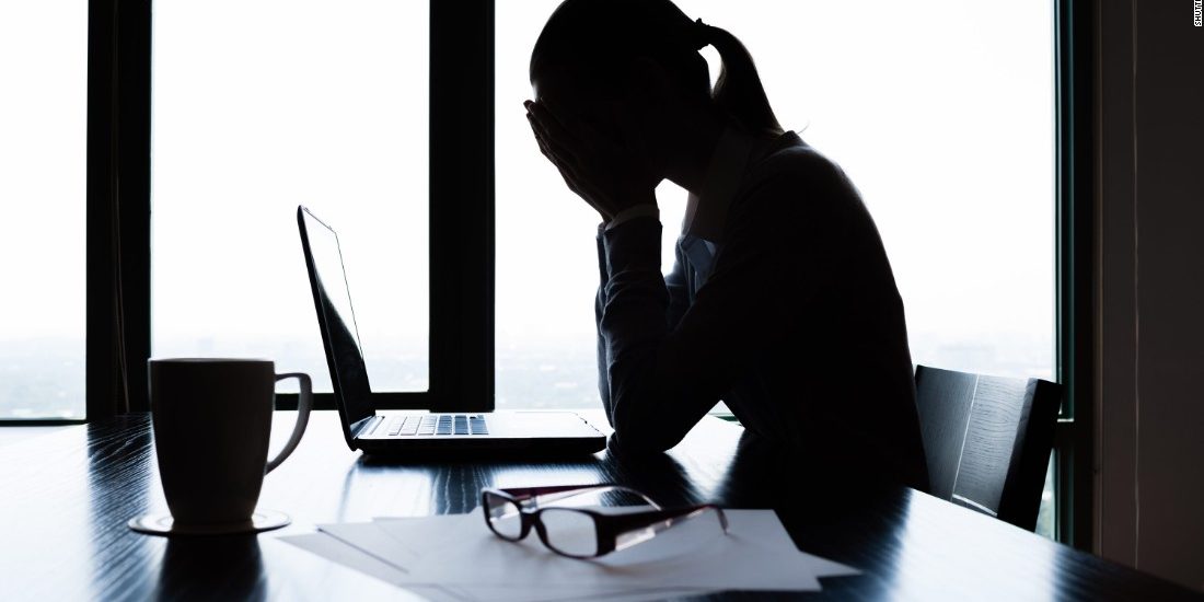 A worried lady sitting on a chair covering her face with her hands