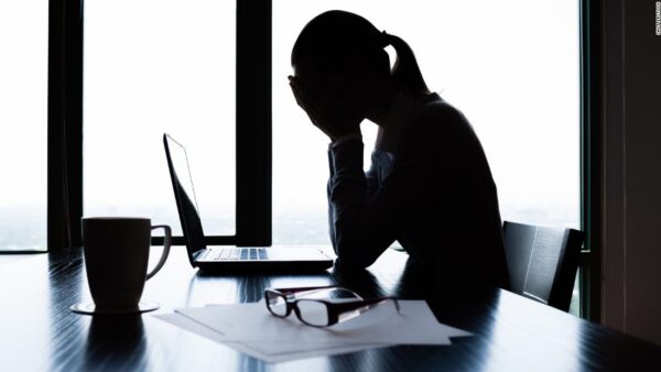 A worried lady sitting on a chair covering her face with her hands