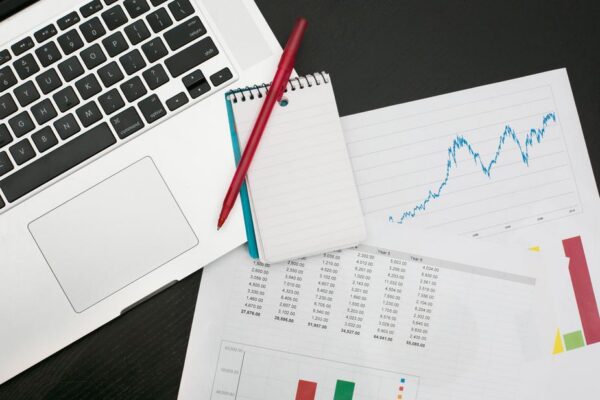 A laptop, business and finance reports and a pen