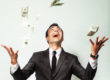 A man throwing cash up and smiling