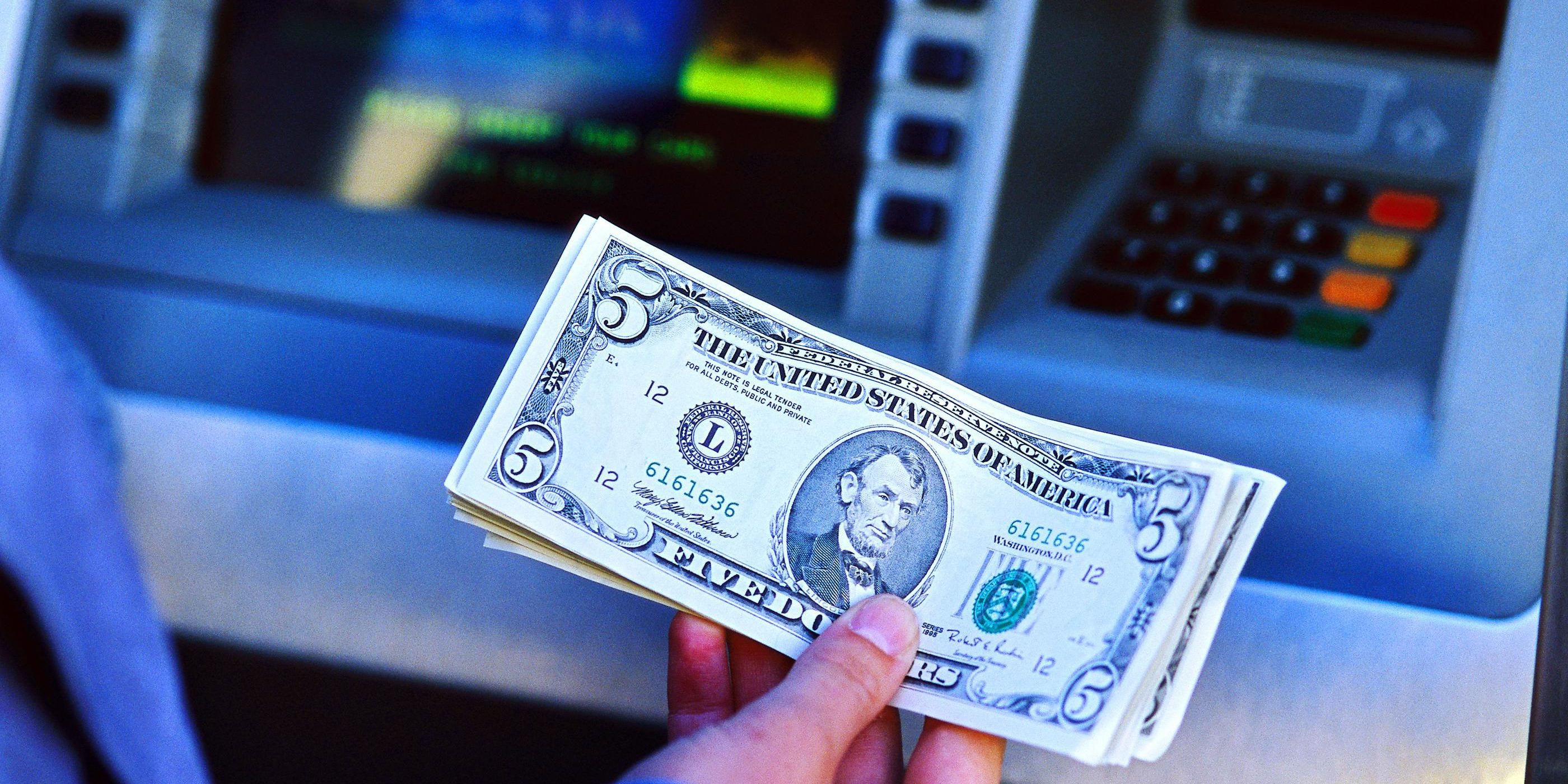 Hand holding cash Hand holding cash in front of ATM