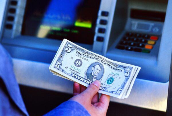 Hand holding cash Hand holding cash in front of ATM