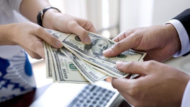 Two pair of hands holding US Dollars