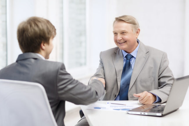 two men shaking hands in office Old man and young man shaking hands in office