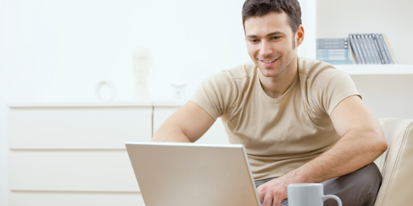 A smiling man using his laptop
