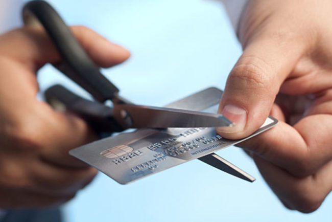 A person cutting his card with scissor A person's hand cutting a credit card with scissor
