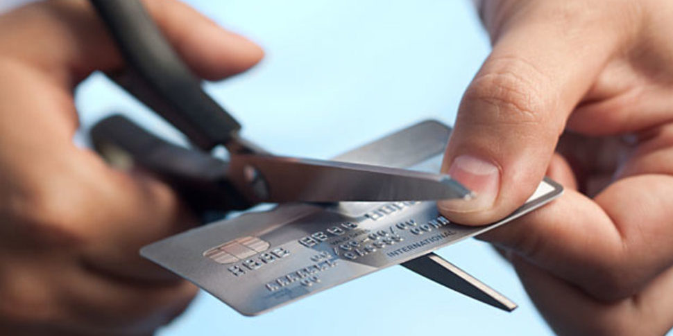 A person's hand cutting a credit card with scissor