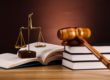 A beam balance and gavel placed on books over a table