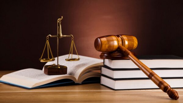 A beam balance and gavel placed on books A beam balance and gavel placed on books over a table