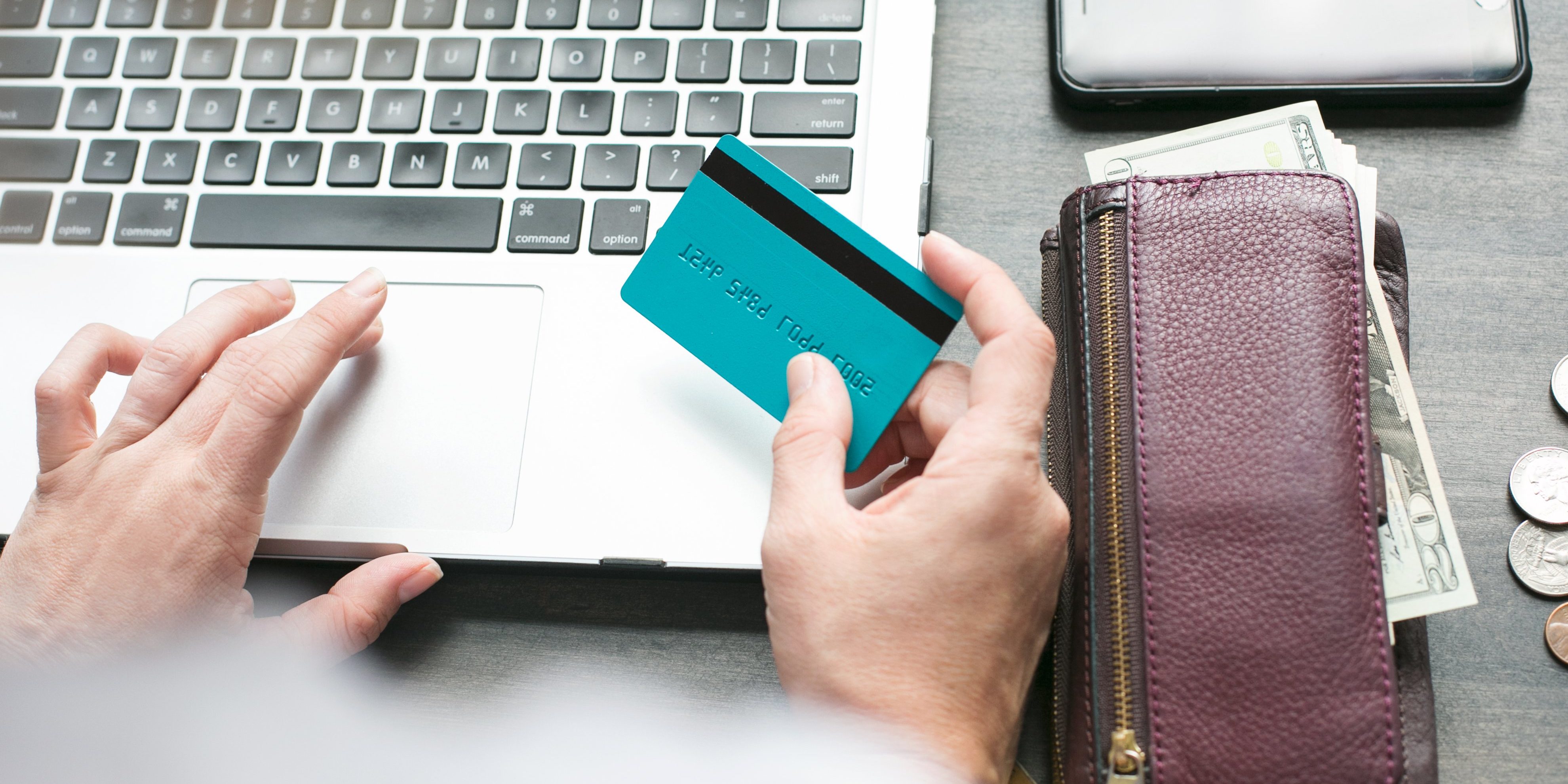 A hand using laptop and other holding credit card