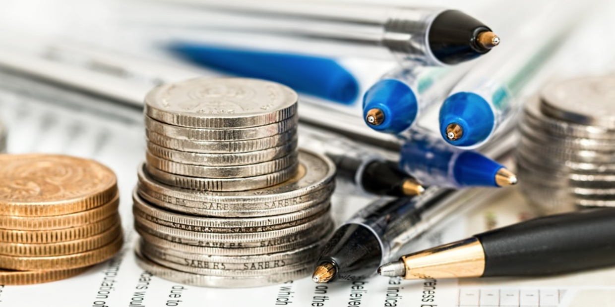 Some coins and pens placed over a paper