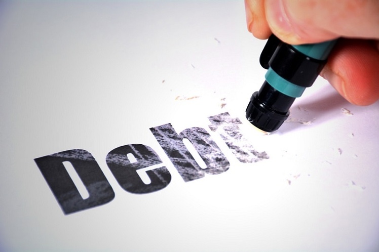 Fading word debt A pen in hand trying to erase the word debt