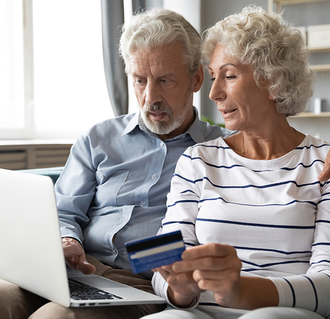 Husband and wife sitting on couch having video conference on laptop with Strategic Capital, one of the nation's top annuity buyout companies