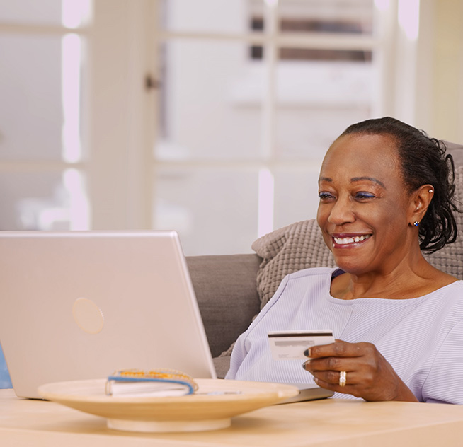 Black lady smiling while searching on her laptop for companies that buy out annuities.